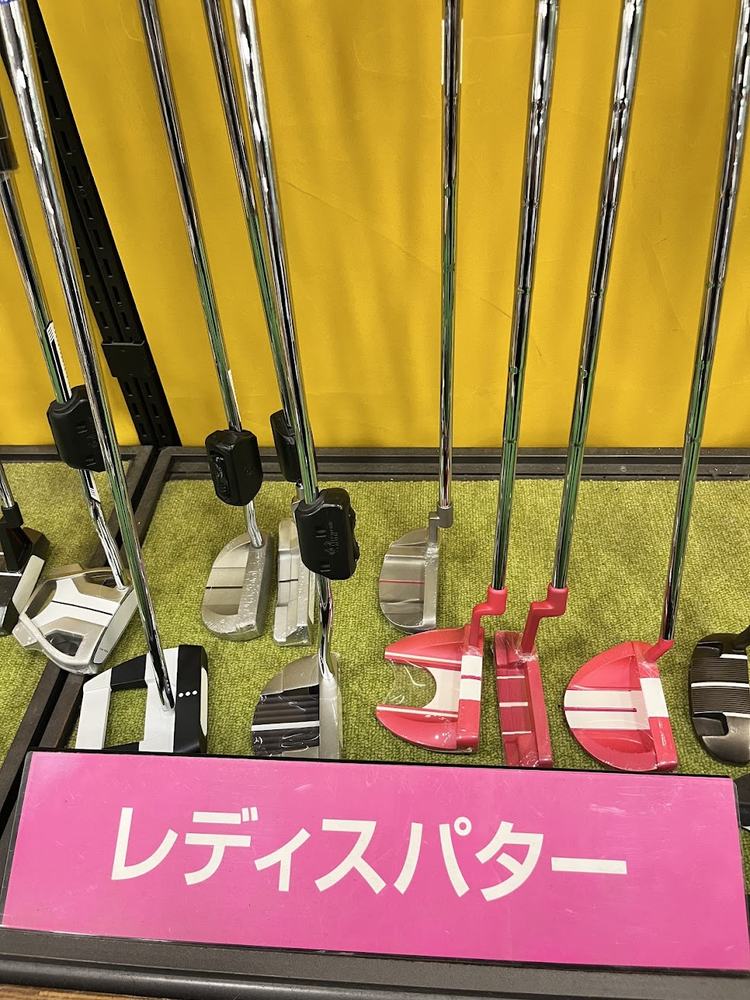 ゴルフショップのレディースパター売り場。「レディスパター」の札の奥に、ピンクやシルバー、白黒のパターが並んでいる